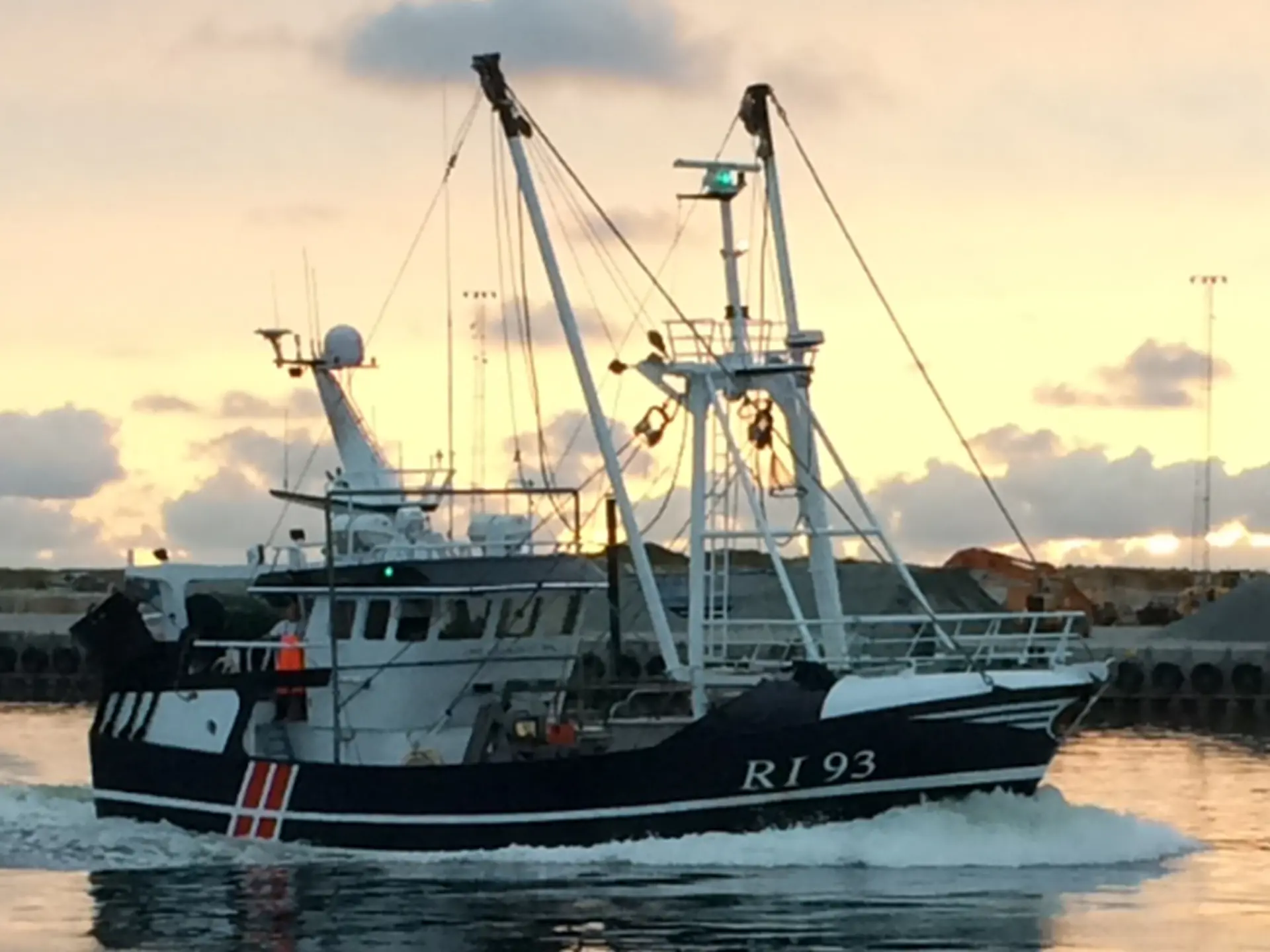 Fiskekutter i vandet med solnedgang